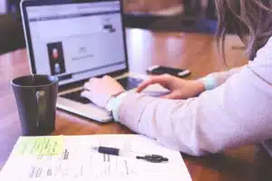 Person beim Arbeiten am Laptop mit Notizen.