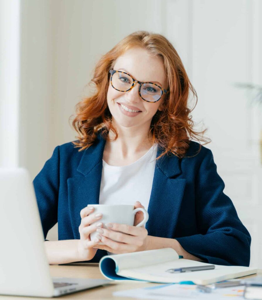 Woman smiling with coffee at a desk