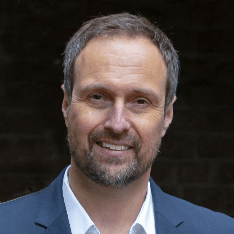 Lächelnder Mann in Anzug vor dunklem Hintergrund